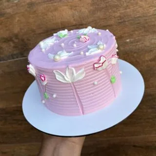 Bolo rosa com flores brancas aplicadas em chantininho