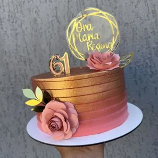Bolo dourado e rosé com topo de flores de papel e plaquinha acrílica com o nome