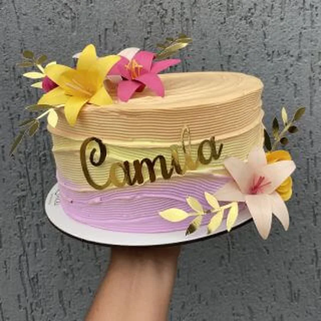 Bolo em degradê amarelo e roxo com flores de papel e nome em acrílico dourado