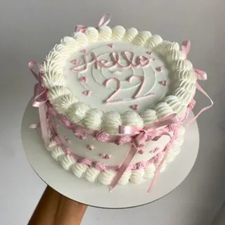 Bolo branco estilo vintage com laços rosa e escrita 'Hello 22'
