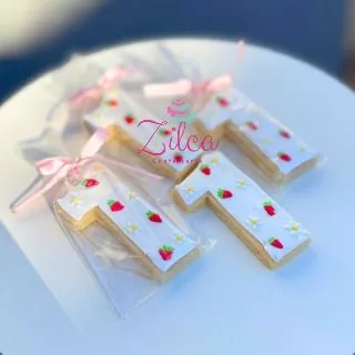 Biscoito decorado em formato do número 1, com morangos em glacê real, embalado com laço